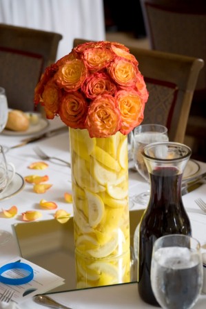 Burnt orange floral centerpiece in a modern lemon filled vase