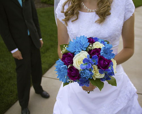 bride holding autumn wedding bouquet with blue, dark purple and white flowers