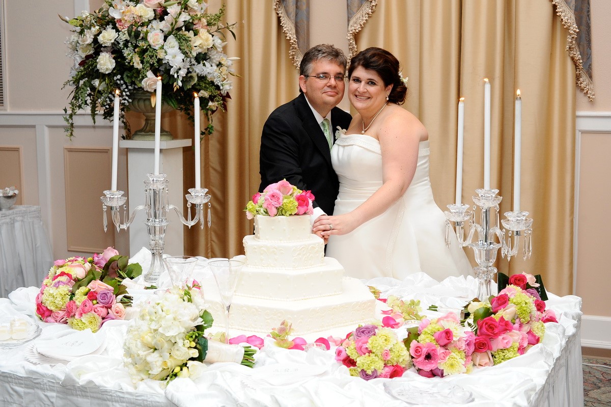 Bride and Groom at Wedding Cake Table with pink,green and white bridal bouquets
