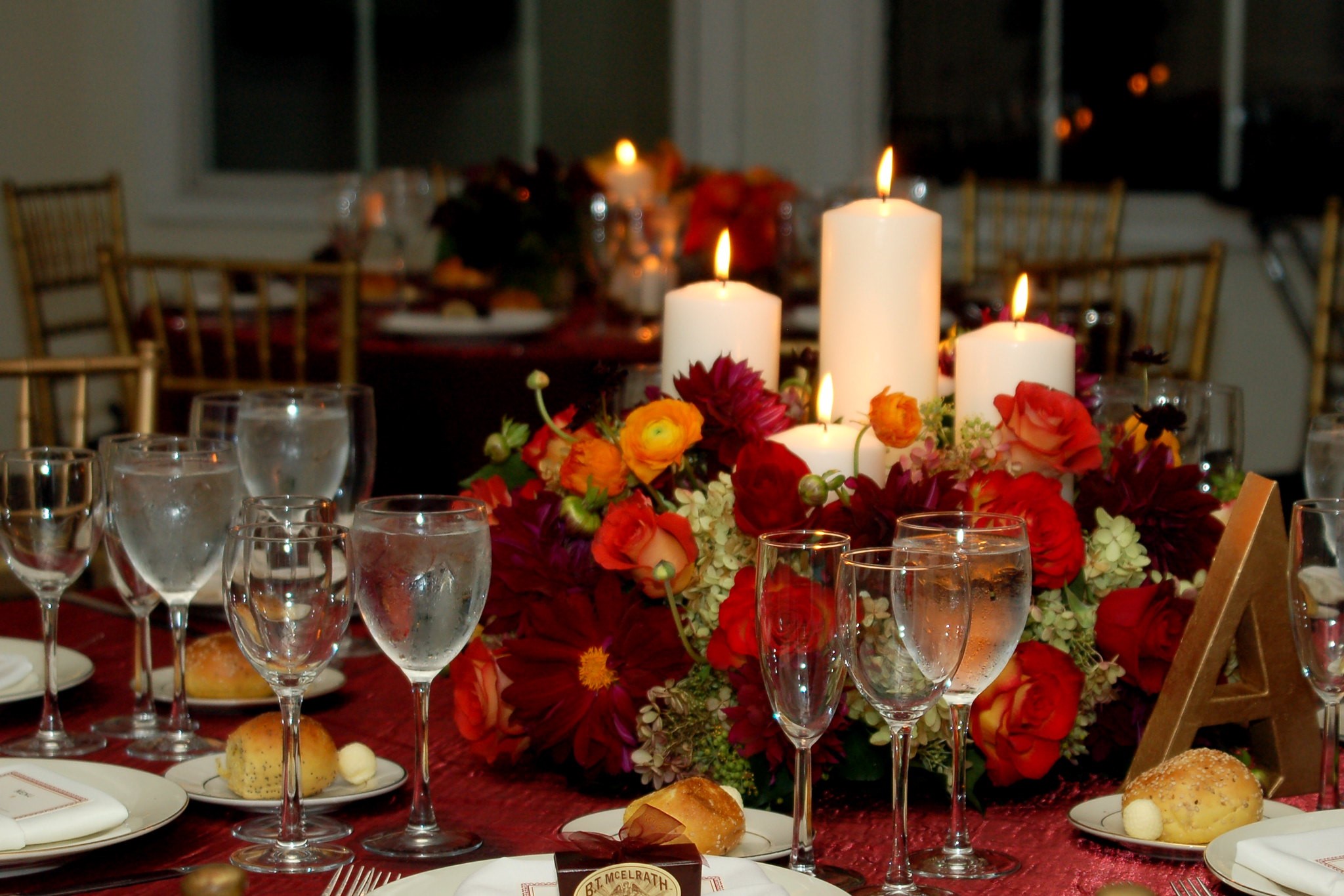 Fall Wedding Centerpiece - White Candles Surrounded By Red and Orange Flowers