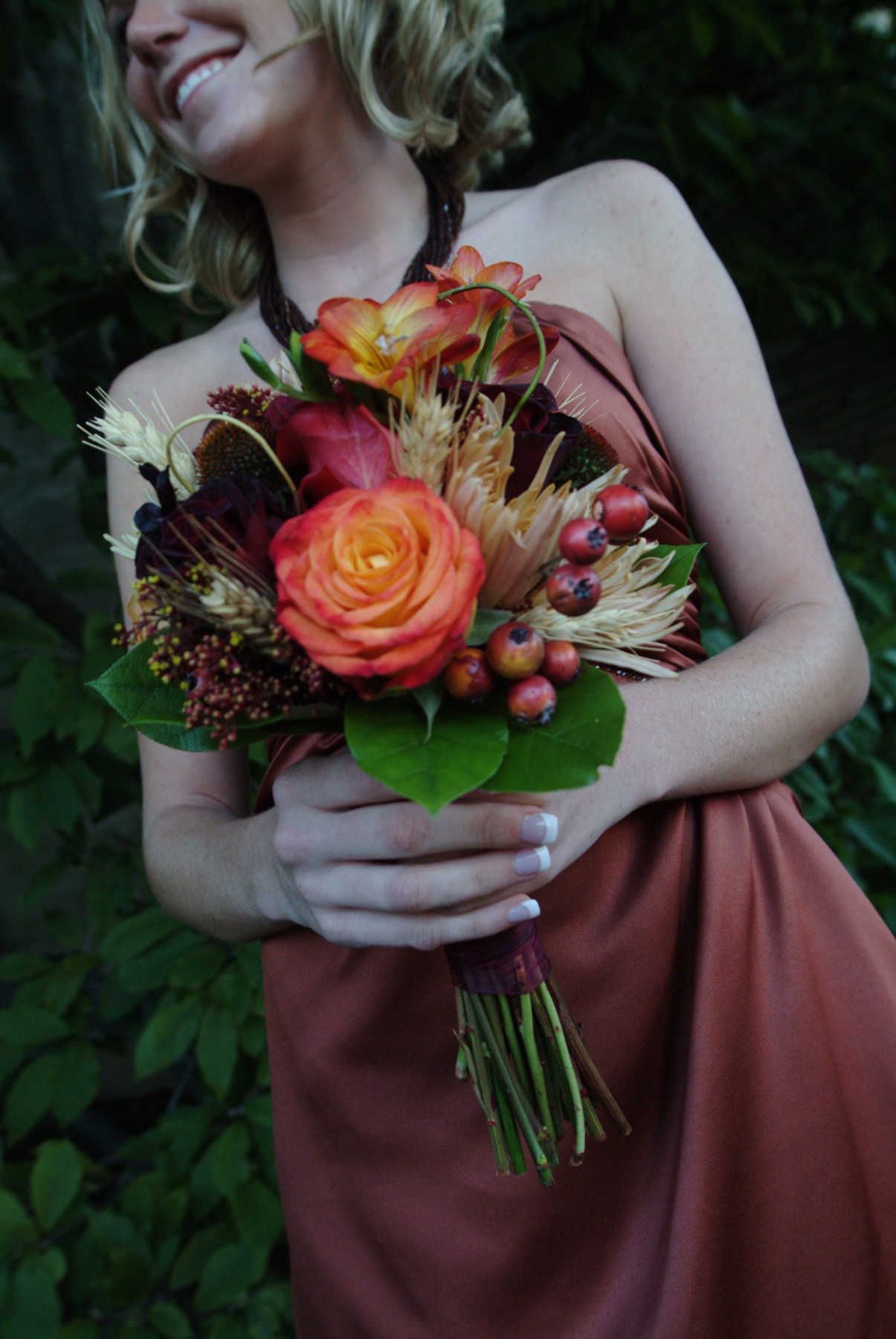 Bridesmaid with Dark Red and green floral bouquet with pops of orange