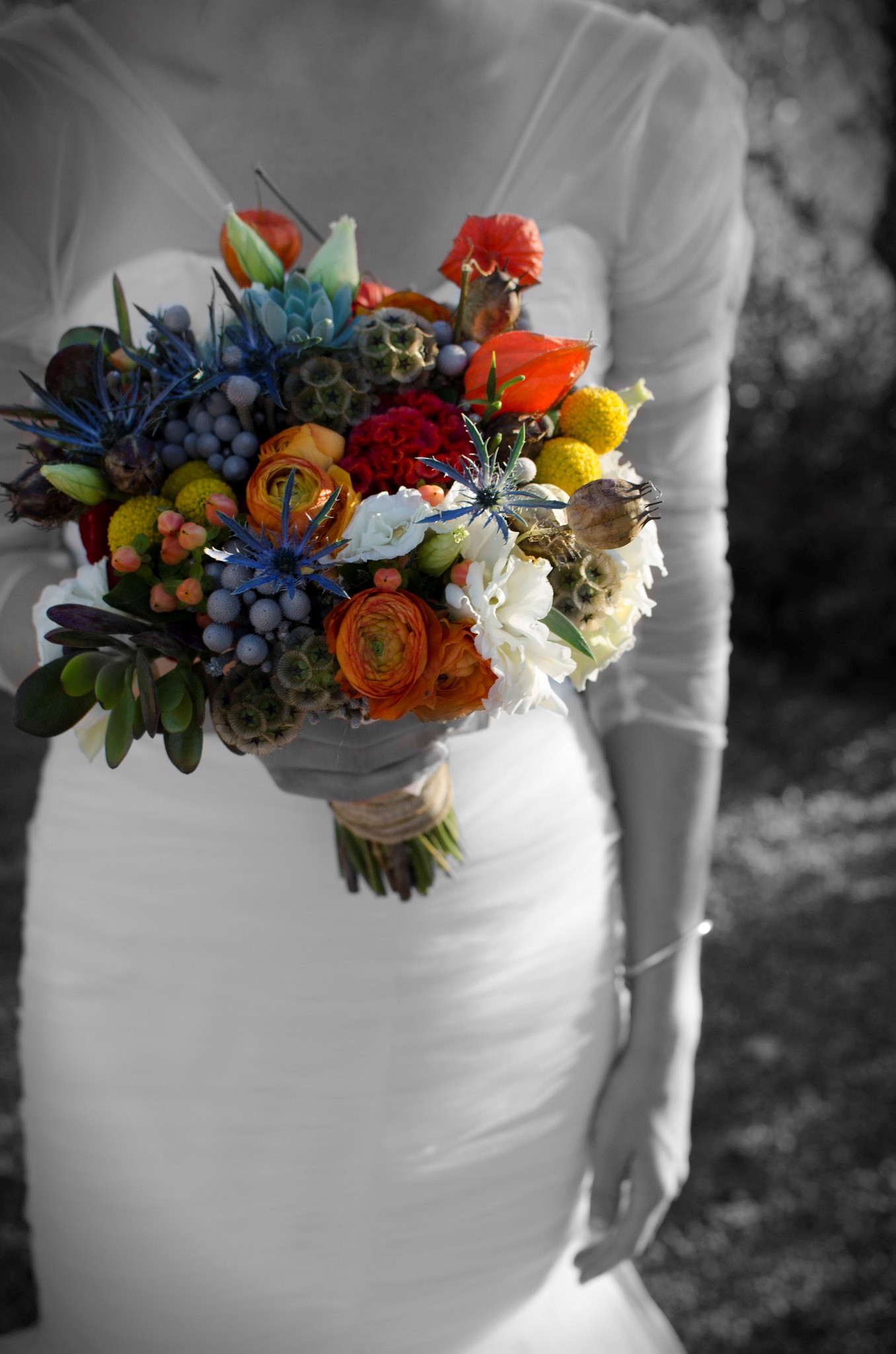 Dramatic Wedding Photo of Bride in muted filter with beautiful fall wedding bouquet in vivid colors or green, orange, purple, white and yellow