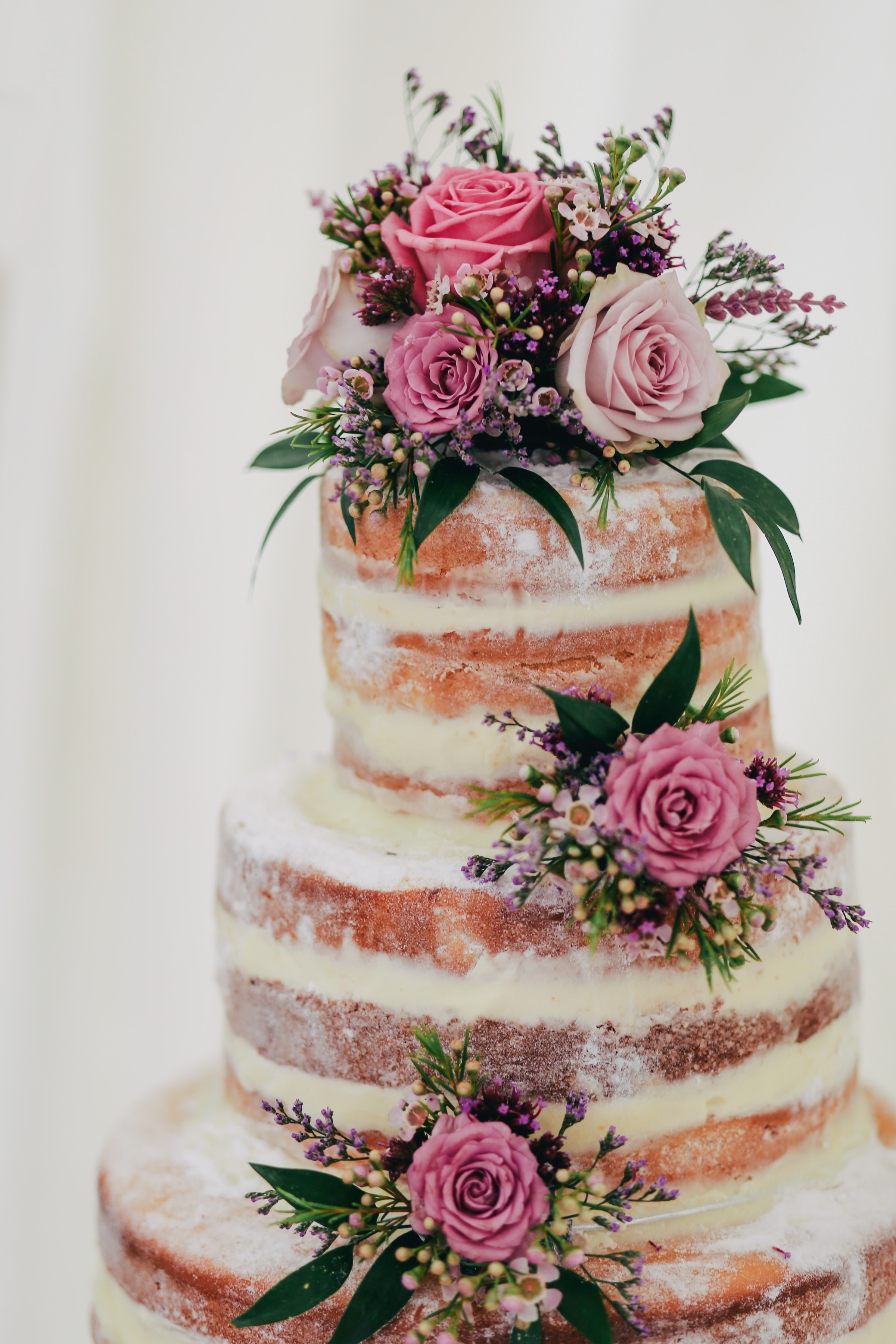 Naked Wedding Cake With Pink and Purple Flowers