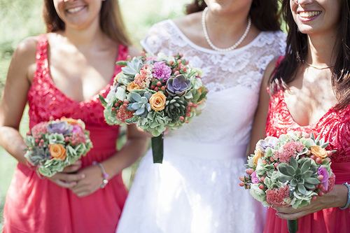 bride and bridesmaid in red bridesmaid gowns holding wedding bouquets