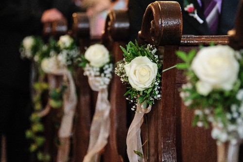 Church Pews With White Wedding flowers