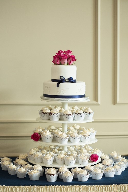 Tiered White Cupcakes With White wedding Cake and Flowers