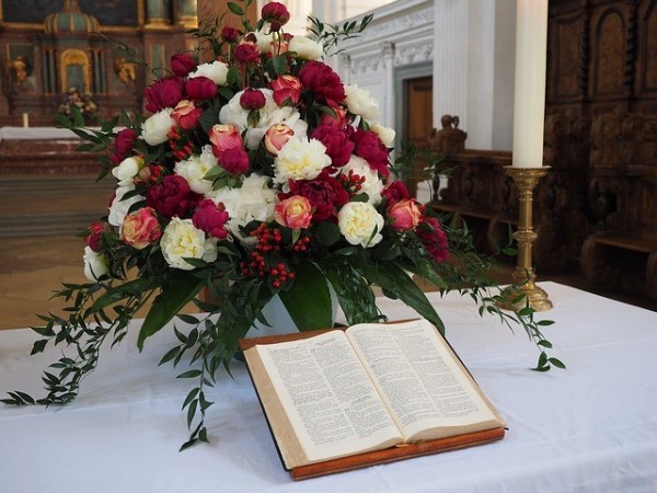 Red and White Bouquet Cascading over Wedding Bible at Church Wedding