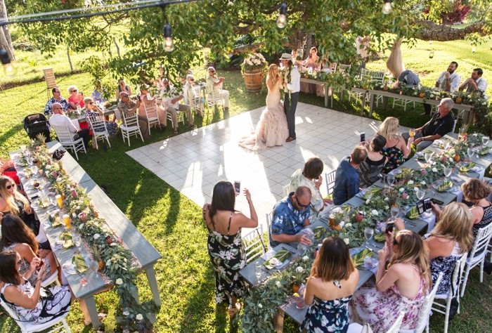 Beautiful Outdoor Wedding Reception, rectangle tables framing dance floor - tables covered in flowers and greenery.