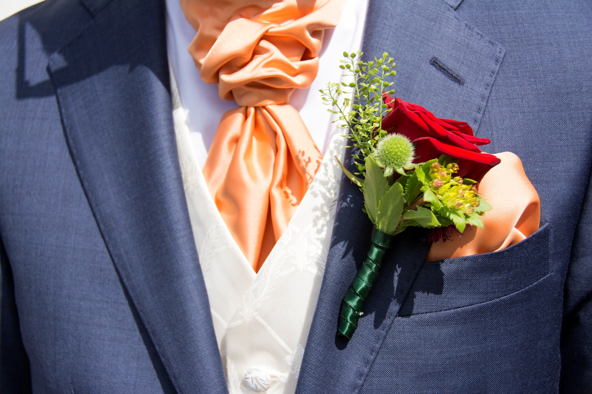 Man in Blue suit with Peach Tie and modern red and green Boutonniere